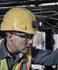 Worker wearing a yellow helmet with 2750C LED Headlamp Hands Free Light With 259 High Lumens in industrial environment