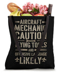 Caution Flying Tools Tote Bag For Aircraft Mechanics filled with groceries, black with bold text and dual handles