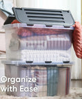 12 Pack Heavy Duty Clear Deep Storage Containers With Secure Hinged Lids 27.5 Quart Snap Close Bins stacked with blankets and towels.