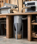 Heavy Duty Industrial Dust Collector That Sucks Up Shop Dust Like A Boss And Ensures Smooth Sailing Workshop Cleanup With Zero Hassle Heavy Gauge Metal Housing And Pro Grade Performance positioned under a workbench.