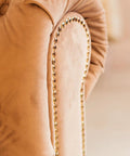 Smooth Upholstery Nailhead Trim Tape 8 Meter Glossy Bronze Decorative Strips adorn a soft beige chair back with shiny nails.