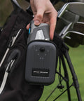 Person attaching Pro ZR Golf Laser Rangefinder With DuraShield Hardshell And Cart Magnet to golf bag, clubs visible