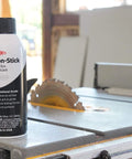 Nonstick Dry Film Lubricant Aerosol 14 oz can on workshop table near saw, ultra thin dirt resistant coating for metal parts