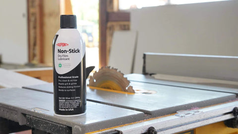 Nonstick Dry Film Lubricant Aerosol 14 oz can on workshop table near saw, ultra thin dirt resistant coating for metal parts