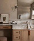 Bathroom vanity with marble countertop, featuring brown leather drawer pulls on wooden cabinets, large mirror above sink area.