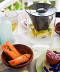 10 Cup Filtered Water Pitcher With Bamboo Handle, BPA Free Plastic, next to a fruit bowl, on a dining table outdoors