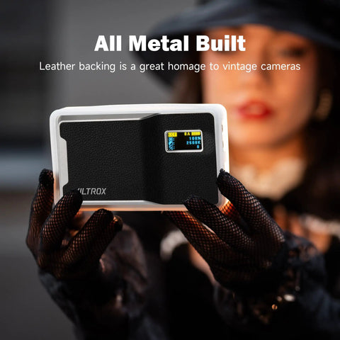 Close-up of a person holding the On Camera RGB LED Light With 6000mAh Battery, App Control Via Bluetooth, All Metal Portable Video Lighting Panel For Filming And Photo Shoots, Retro 08X, 8 Hour Battery Life At 50 Percent Brightness, showing leather back and display screen.