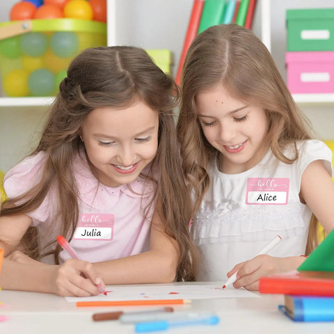 Two girls wearing Light Pink Hello My Name Is Stickers Set, 300 Pcs Name Tag Labels On A Roll For Back To School drawing together.