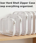 Clear Hard Shell Makeup Pouch Set, Transparent Cosmetic Organizers, Crush Resistant Travel Toiletry Cases, Durable zippered cases lined up on shelf.