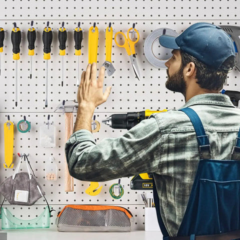 Man organizing tools on a pegboard using Heavy Duty Pro Grade Metal Pegboard Hooks 25 Pack, 4 Inch Peg Board Hangers For Hanging, Fits One Eighth Inch Pegboards, Great For Garage Shop Office Kitchen Crafts Organization, Galvanized Silver.