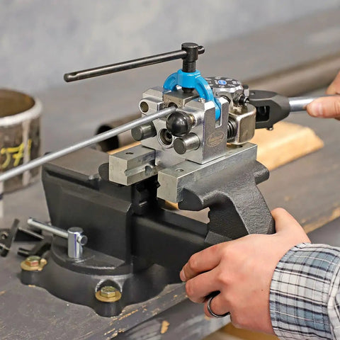 Rock Solid Five Inch Workbench Vise With Knockout Grip Smooth Non Marring Jaws And Heavy Duty Locking Mechanism in use on a wooden bench.