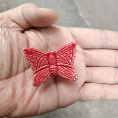 Top Shelf Red Butterfly Cabinet Knobs And Vintage Drawer Pulls Set Of Six With Glossy Ceramic Finish and Zinc Alloy Base held in a hand
