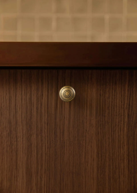 Real Deal Antique Brass Cabinet Knobs 1 1/4 Inch Round Sunburst Design on a wooden cabinet door.