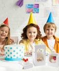 50 Pack Cupcake Containers With Windows, White boxes with cupcakes and kids in party hats, showcasing desserts.