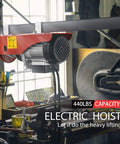 Installed red electric hoist mounted on overhead beam with cable and hook, 440 lb capacity
