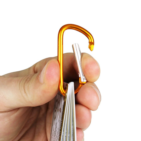 Hand holding Outdoor Knot Cards 22 Knots For Camping Backpacking And Scouts Easy Step By Step Diagrams And Real World Tips with carabiner clip.