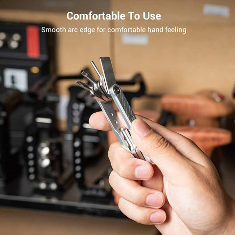 Hand holding Compact Seven Tool Folding Set With Screwdrivers And Hex Keys For Photographers On The Go in a workshop.