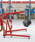 Shop Essential Two Ton Hydraulic Engine Hoist With Six Swivel Rollers And Quick Fold Frame lifting an engine in a garage.