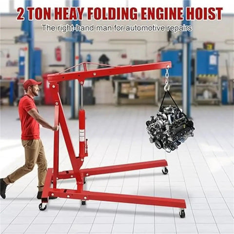 Shop Essential Two Ton Hydraulic Engine Hoist With Six Swivel Rollers And Quick Fold Frame lifting an engine in a garage.