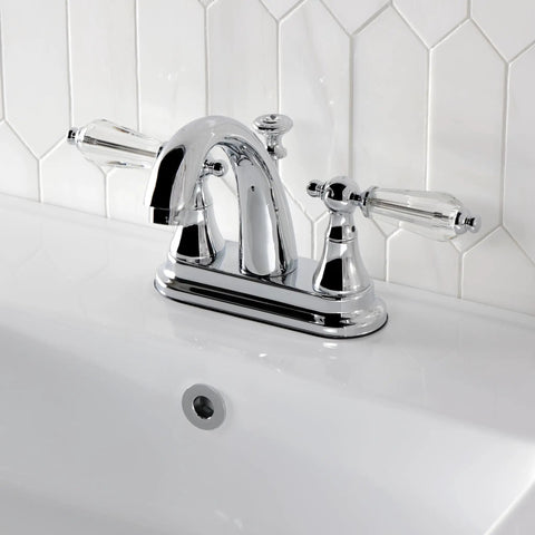 Chrome faucet with crystal lever handles on a white sink with hexagonal tile backsplash.