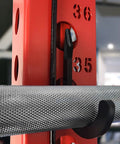 Close-up of black squat rack hook and power rack attachment for DIY storage on 1 inch hole-spaced rack holding barbell