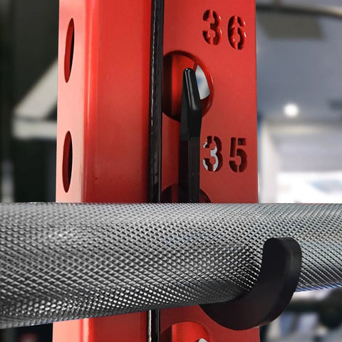 Close-up of black squat rack hook and power rack attachment for DIY storage on 1 inch hole-spaced rack holding barbell