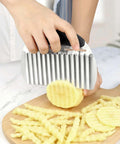 Stainless steel potato crinkle cutter with black handle and large wavy blade for crinkle fries.