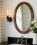 Matte Black Rustic Industrial Wall Sconce Light With Tubular Clear Glass Lampshade in bathroom mirror reflection.