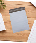 White Poly Mailers 10x14 Inch Waterproof Self Seal Shipping Bags For Apparel And Clothes on wooden surface with notebooks