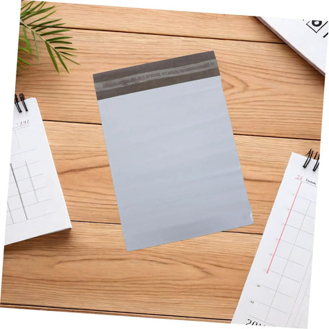 White Poly Mailers 10x14 Inch Waterproof Self Seal Shipping Bags For Apparel And Clothes on wooden surface with notebooks