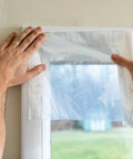 Applying Max Strength Window Insulation Kit For Cold Weather, No-Fuss, Heavy Duty Shrink Film over window frame with clear tape