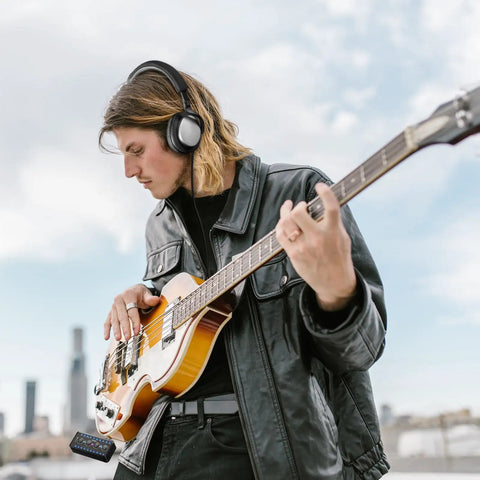 Musician using Compact Guitar Headphone Amp With Multi Effects, IR Loader, Tuner, And Rechargeable Battery outdoors