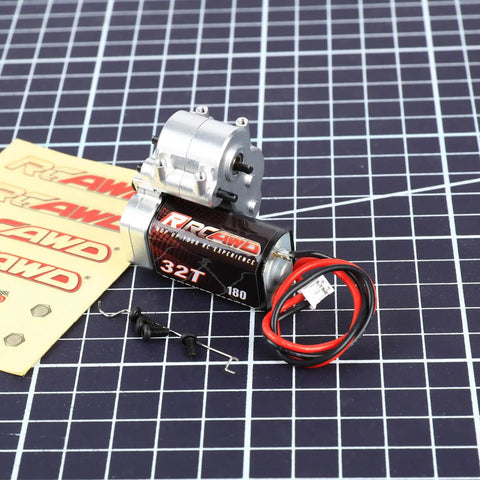 180 Motor 32T Transmission Metal Gearbox Combo for FCX24 Smasher V2 with wires and screws on grid surface.