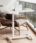 Mobile Standing Desk On Wheels, Sit Stand Laptop Table With Lockable Casters, Adjustable 7 Level Height From 27.5 To 36.2 Inches, Portable Overbed Bedside Workstation, White, on a balcony next to a wicker chair.
