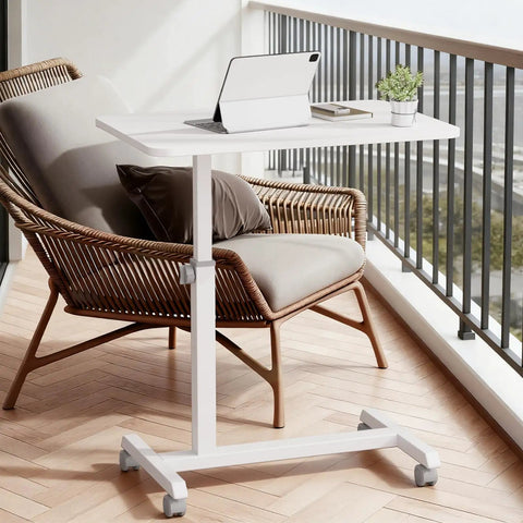 Mobile Standing Desk On Wheels, Sit Stand Laptop Table With Lockable Casters, Adjustable 7 Level Height From 27.5 To 36.2 Inches, Portable Overbed Bedside Workstation, White, on a balcony next to a wicker chair.