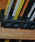 Box Of Fifty H2 Homer Helpers For Electrical Wire Management, black plastic cable organizer with wiring, mounted on wooden beam.