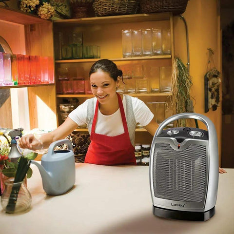 Oscillating Ceramic Tabletop Space Heater With Adjustable Thermostat Carrying Handle Two Quiet Heat Settings And Fan Only Mode 11.6 Inches Silver Compact Space Saving Home Heating Solution on a kitchen countertop with a woman smiling in the background.