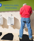 Man using urinal with 10 Pack Urinal Mats For Men Non Slip Urinal Floor Mats For Commercial Restrooms Highly Absorbent Durable With Waterproof TPR Backing Keeps Urinal Floors Dry And Slip Free Black visible on floor.