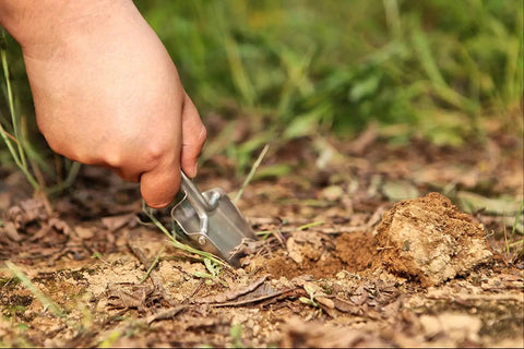 Hand using Lightweight Folding Shovel For Camping And Gardening Handy Compact Trowel Tool to dig in the soil