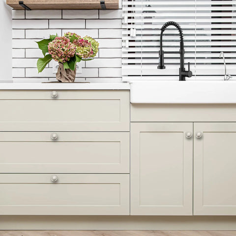 Sleek brushed nickel knobs on modern cabinets in a kitchen with a sink and decorative flowers for style enhancement.