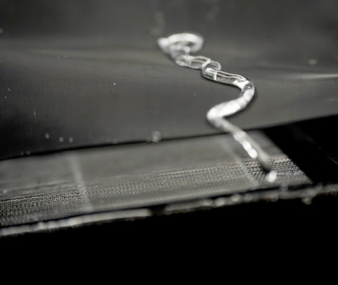 Close-up of water flowing off waterproof and dustproof hydrophobic prefilter mesh for air filters 18 by 18 inch fabric.