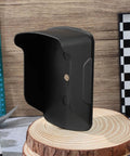Black plastic Waterproof Doorbell Cover Rain Guard for outdoor devices shown on wooden surface, protects from elements.