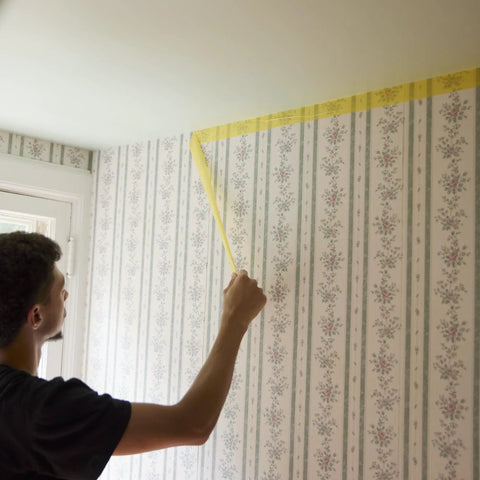 Person applying Delicate Surface Painters Tape With PaintBlock Technology For Sharp Lines No Bleed Low Adhesion to wallpaper edge