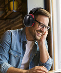 Smiling man wearing Kick Loud Noise To The Curb With Double Layer Over Ear Earmuffs designed for construction and shop jobs.