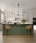 Modern kitchen with green island, pendant lighting, wicker chairs, and white cabinetry featuring Five Inch Brushed Nickel Cabinet Pulls.