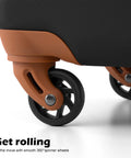 Luggage spinner wheel close-up on a brown frame of a black textured hardside suitcase.