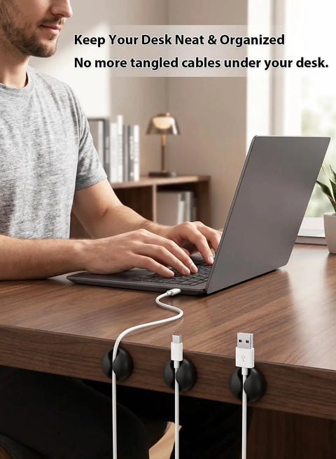 Man using desk with Six Pack Black Cord Organizer Clips For Cables And Chargers neatly securing cables on wooden surface