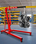 Built Tough Folding Engine Hoist With Quick Adjust Leveler And Rock Solid 6400 Lbs Alloy Steel Capacity, engine suspended in a garage.