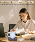 Electric Coffee Mug Warmer With 15 Oz Ceramic Cup And Removable Cork Base on desk beside a woman reading, keeping coffee hot.
