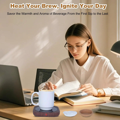 Electric Coffee Mug Warmer With 15 Oz Ceramic Cup And Removable Cork Base on desk beside a woman reading, keeping coffee hot.
